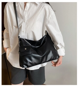 Detailansicht einer schwarzen matten PU-Schultertasche mit Zierkette und Mini-Zubehörtasche