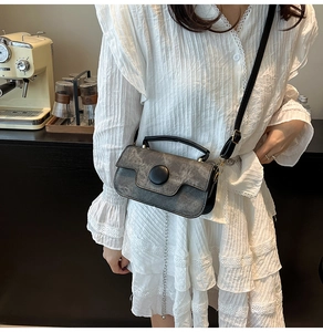 Détail d'un mini sac rétro gris foncé avec boucle ronde et chaîne porté par un modèle