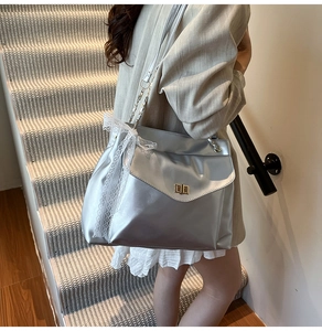 Détail du sac argenté avec finition métallisée, fermoir doré et nœud en dentelle blanche