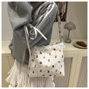 Détail du sac bandoulière en toile blanche avec motif ours et bordures en dentelle