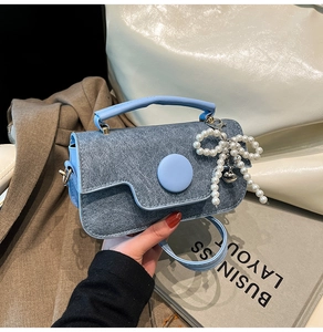 Détail du mini sac bleu clair en texture denim avec nœud perlé et breloque cœur