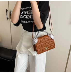 Detail of brown quilted crossbody bag featuring a gold buckle and silk scarf handle wrap