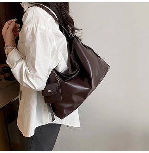 Detail of dark brown tote bag with mini pouch accessory and soft matte leather texture