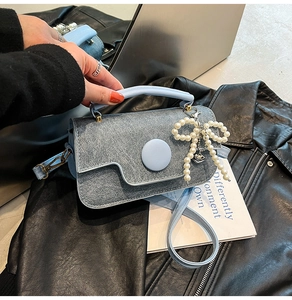 Détail du mini sac en denim bleu avec nœud en perles blanches et poignée en similicuir