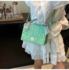 Detail of mint green quilted handbag featuring a decorative floral silk scarf handle