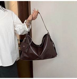Detail of dark brown faux leather tote bag with silver chain pouch accessory