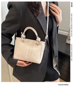 Detail of off-white lychee texture leather bucket bag with fashion print and handle