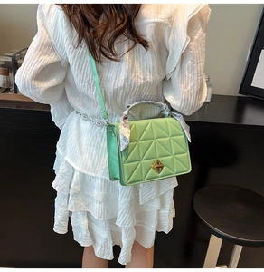 Detail of light green quilted crossbody bag with floral scarf handle and metal clasp
