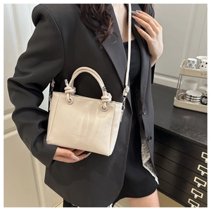 Détail du mini sac seau beige en cuir grainé avec logo embossé et bandoulière élégante