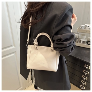 Vue détaillée du sac crème en cuir grainé avec une poignée nouée élégante