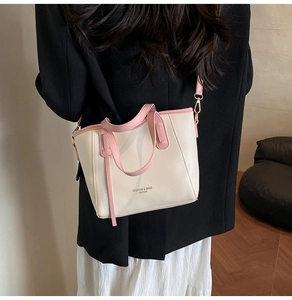Borsa a tracolla in pelle beige e rosa con manico e tracolla indossata da modella
