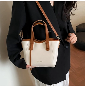 Detail of a chic cream and brown bucket bag worn by a model in a formal outfit