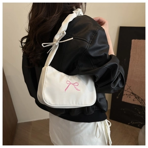 Dettaglio del ricamo fiocco rosa e tracolla elegante su borsa a spalla bianca
