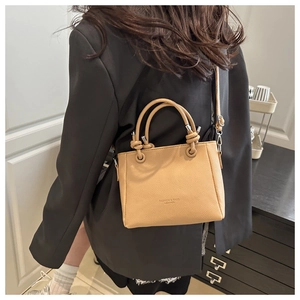 Détail du sac seau beige en cuir grainé avec poignées nouées et bandoulière élégante