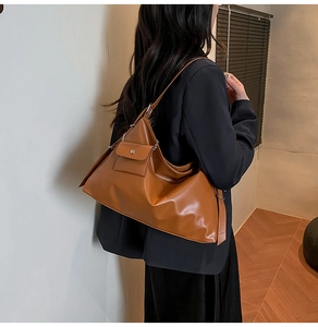 Detailed close-up of brown faux leather shoulder bag with side metallic snap button pocket