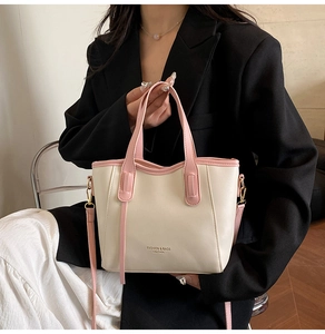 Detail of cream tote bag with pink straps showing fashion leather text and stitching