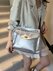 Sac bandoulière argenté brillant avec fermoir doré et nœud en dentelle blanche