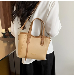 Detail of two-tone bucket bag showing leather texture and adjustable shoulder strap