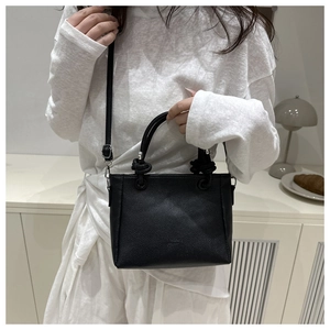 Détail du sac seau noir en cuir grainé avec poignées nouées et bandoulière amovible