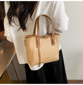 Detail of khaki tote bag with dual handles and shoulder strap shown on model in cafe