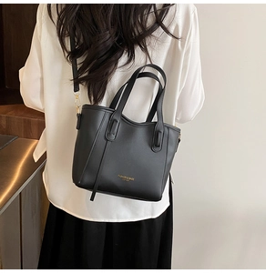 Detailed view of black faux leather tote bag with gold lettering shown on model