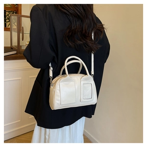 Mannequin portant un sac Boston crème avec un blazer noir, vue de côté et détails du cuir