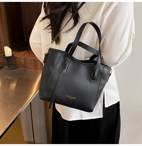 Close-up of black lychee texture leather tote bag with elegant gold lettering detail