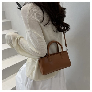 Detailed view of a vintage brown leather handbag with cylindrical handles and silver hardware