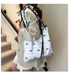 Detail of white tote bag with black polka dots and ruffled floral shoulder strap