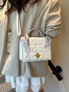 Quilted white crossbody bag with silk scarf handle on model in minimalist setting