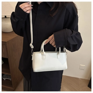 Close-up of white leather tote bag with FASHION lettering and removable strap