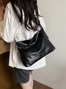 Black leather hobo bag with silver chain mini pouch shown on shoulder from behind