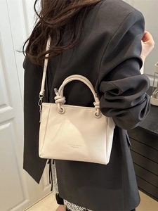 Sac seau beige chic en cuir grainé avec poignée nouée et bandoulière réglable élégante