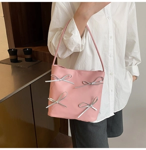 Close-up of pink bucket bag featuring four decorative silver 3D bows on synthetic leather