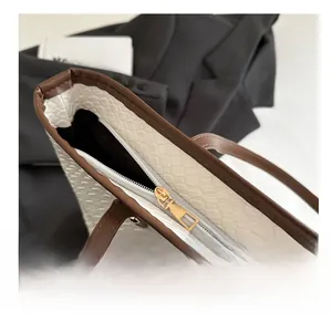 Close-up of golden metal zipper and brown leather trim on woven tote bag details