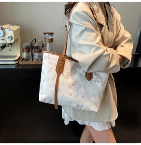 Detail of a white graffiti tote bag with butterfly prints and brown leather straps
