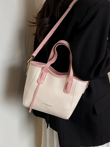 Minimalist beige and pink leather tote bag with shoulder strap worn by a model