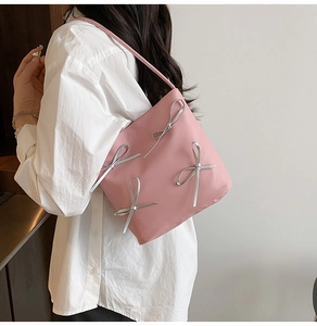 Detailed side view of pink bucket bag with four silver satin bows in balletcore style