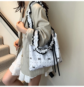 Close-up of bow and polka dot patterns on white shopping bag with ruffled straps