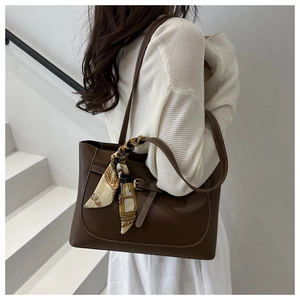 Detail of dark brown leather tote bag featuring a silk scarf bow and elegant white stitching