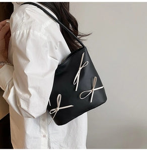 Side view of black bucket bag with cream bows on a model for size and style detail