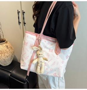 Detail of white tote bag with pink butterfly prints and a cute plush bunny pendant