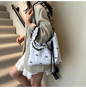 Detail of floral canvas tote bag with ruffled shoulder strap and black bow print accents