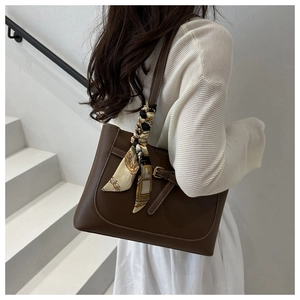 Detail of deep brown tote bag with printed silk scarf wrap on the handle and gold buckle