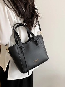 Minimalist black leather bucket bag with top handles shown on model for daily commuting