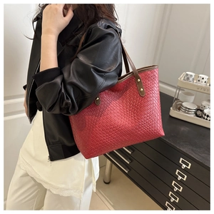 Detail of red woven leather tote bag with dark brown handles and golden metal rivets