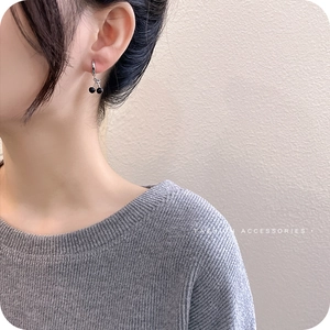 Asymmetric black cherry hoop earrings in silver minimalist style on female model