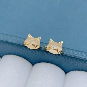 Close-up of cat-shaped gold earrings with cat's eye stone and cubic zirconia details