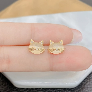 Detailed macro of cat-shaped gold stud earrings with opal stone and zircon accents