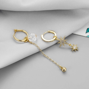 Close-up of asymmetric gold drop earrings with zircon stars and glass bead charms